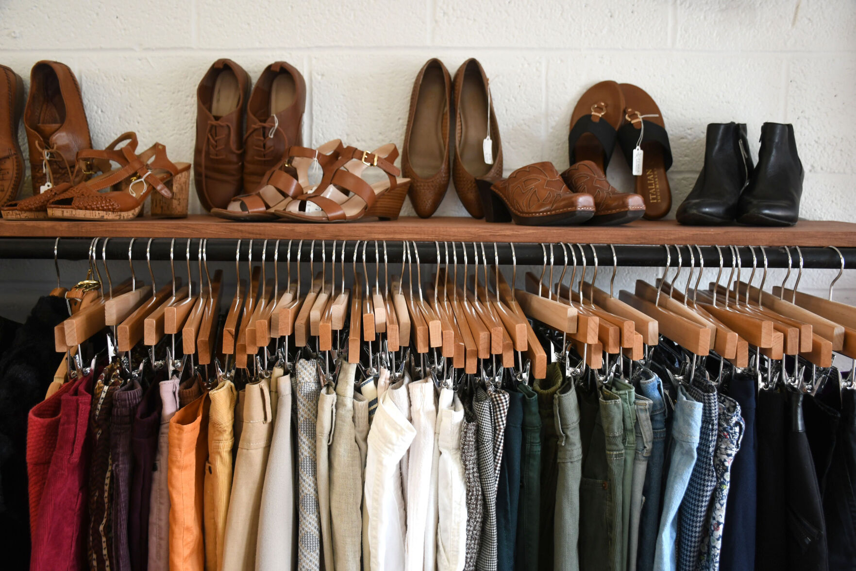 Shoes sit on top of a display of clothes on hangers